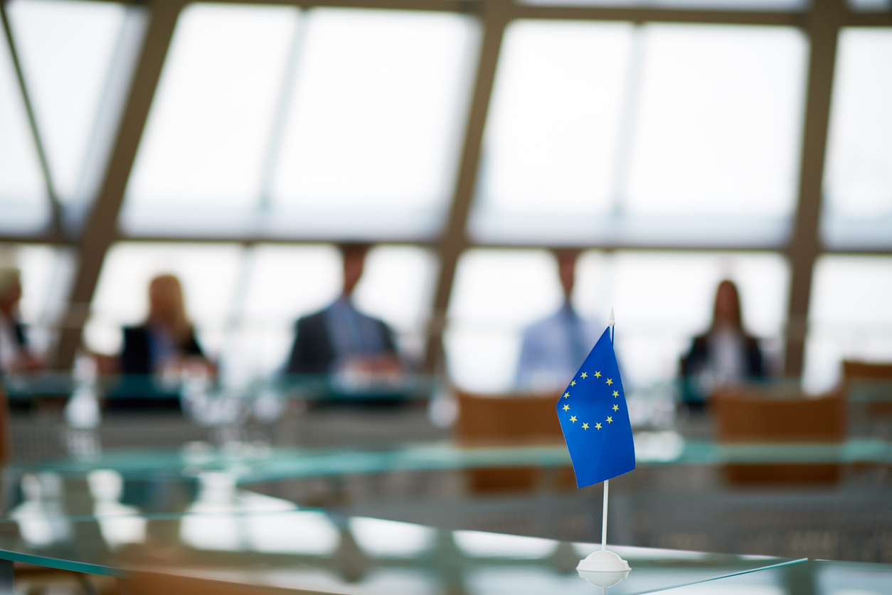 how to read EU trade policy - image depicts officials around a meeting table with an EU flag as the main focal point